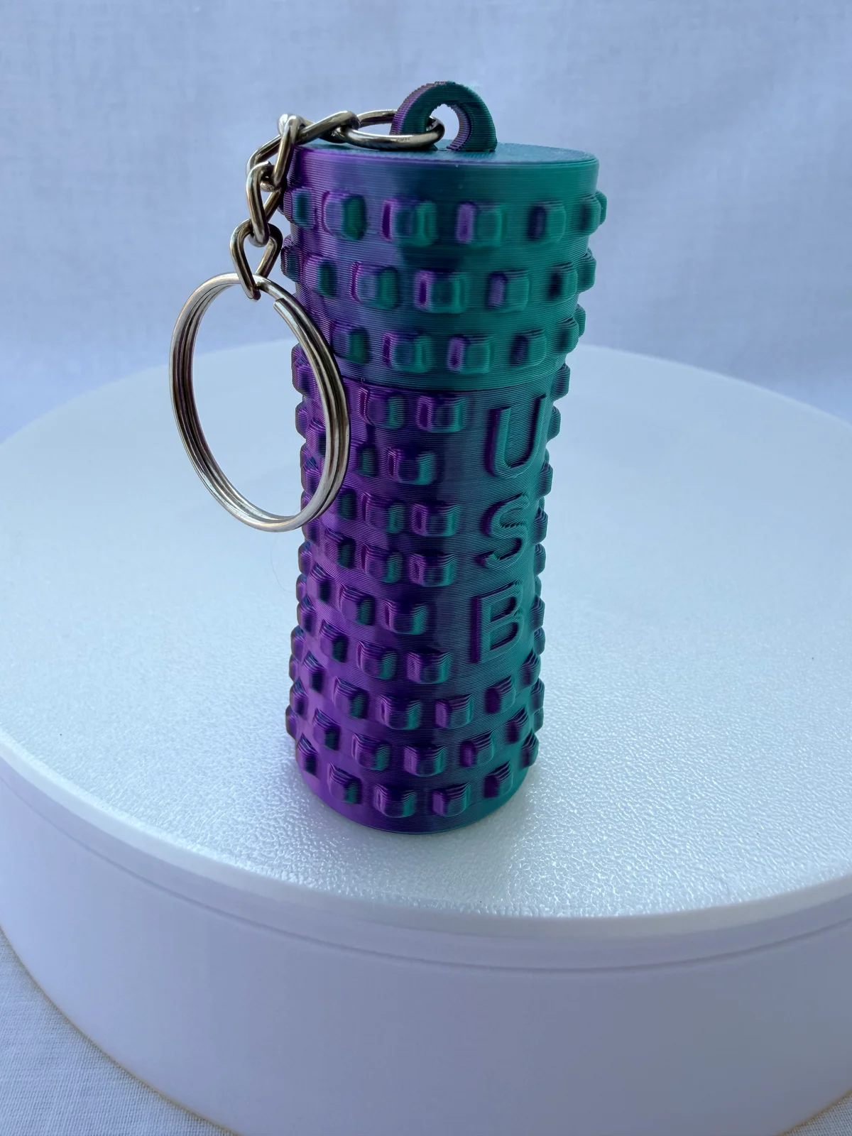 Real Palm Pause hand roller keychain in teal-and-purple silk filament with raised USB initials