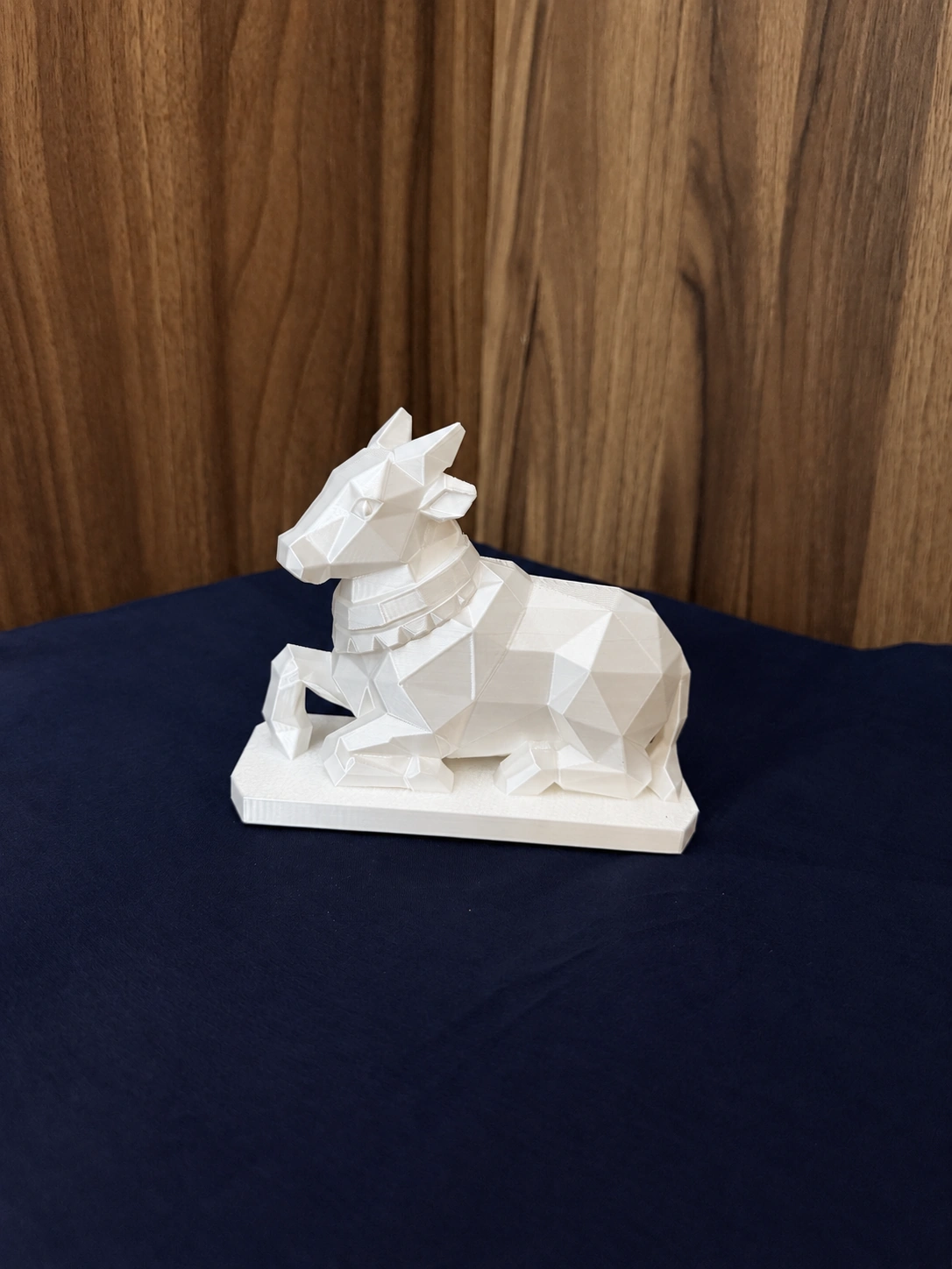 White Low Poly Nandi sculpture in a side three-quarter view, showing its faceted body and rectangular base.
