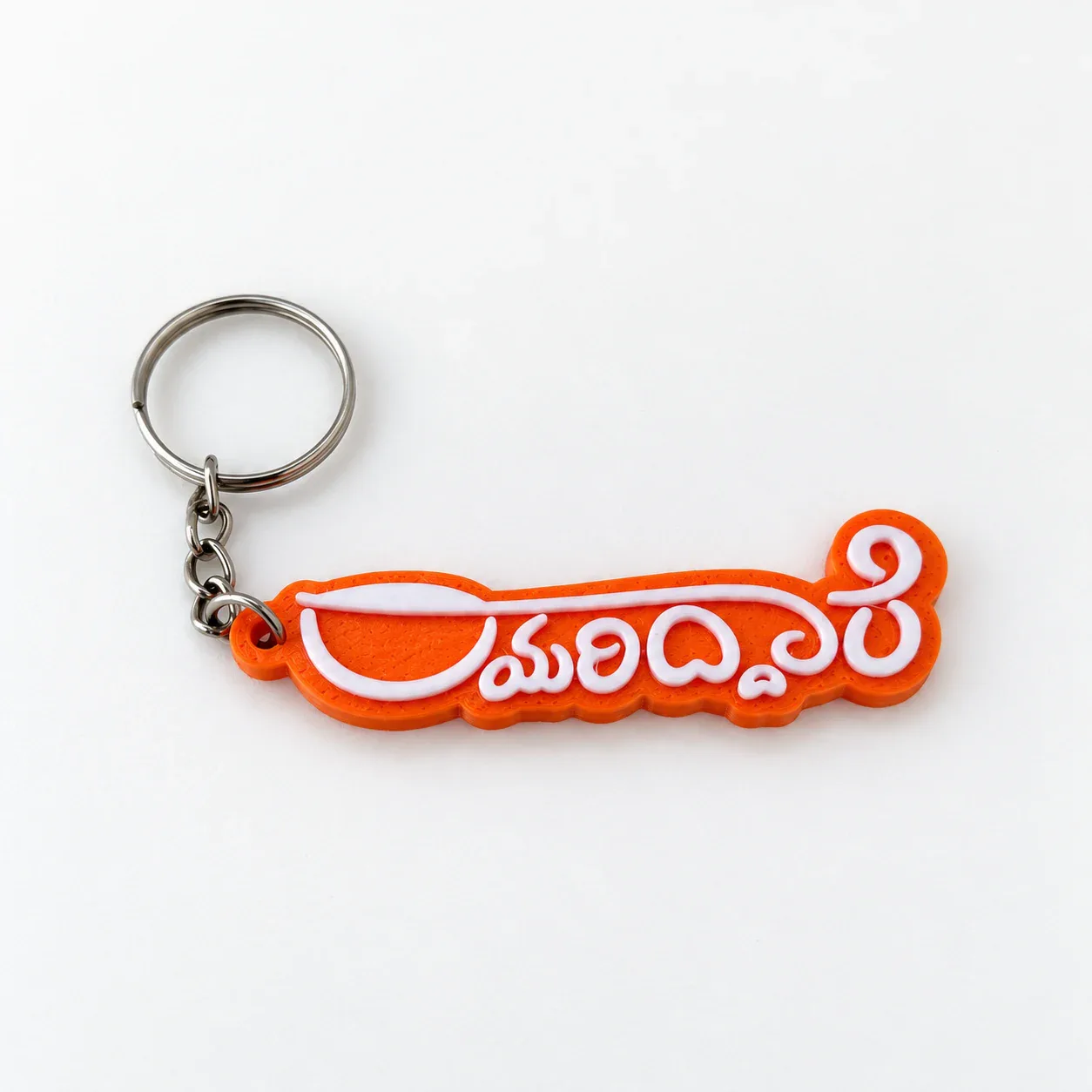 Rayariddare keychain with raised white Kannada lettering on an orange base, silver ring and chain, on a white background